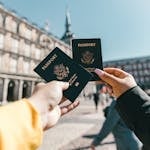 Anonymous tourists showing US passports on street on sunny day